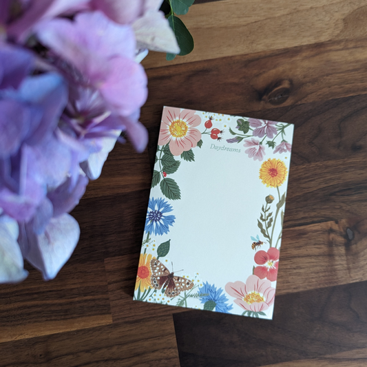 Les motifs floraux délicats et les adorables insectes volants ajoutent une touche de poésie et d'émerveillement à ce carnet.