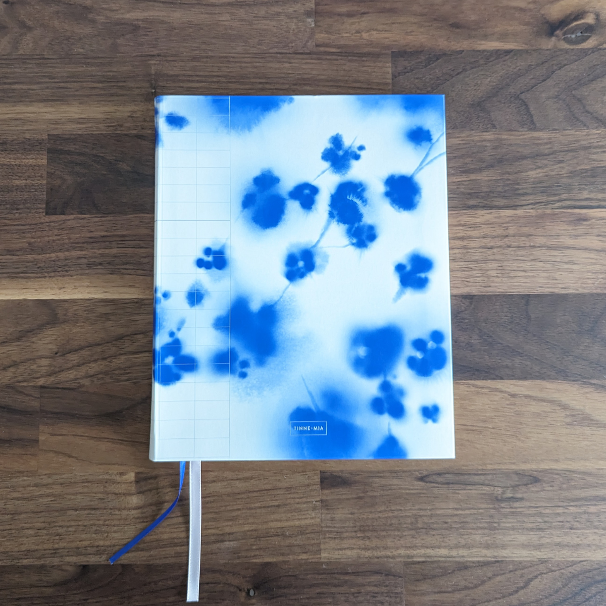 Ce magnifique carnet est orné d'une aquarelle délicate représentant un cerisier japonais en fleurs. Les détails argentés ajoutent une touche d'élégance au devant du cahier, tandis que les signets rose et bleu enlacent subtilement l'ensemble.