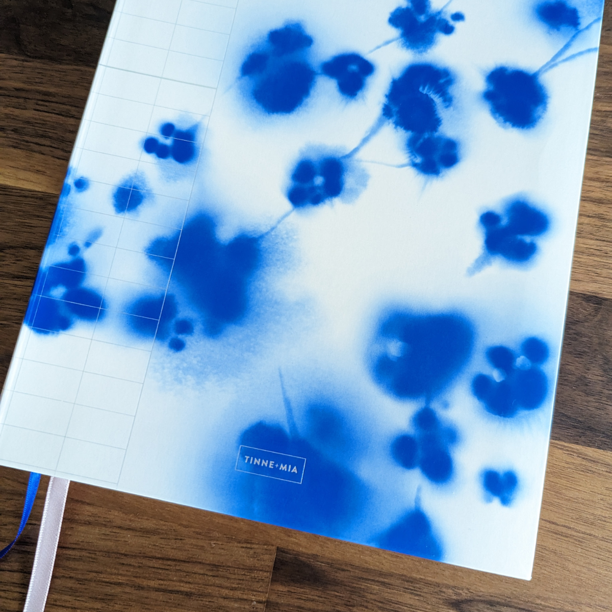 Ce magnifique carnet est orné d'une aquarelle délicate représentant un cerisier japonais en fleurs. Les détails argentés ajoutent une touche d'élégance au devant du cahier, tandis que les signets rose et bleu enlacent subtilement l'ensemble.