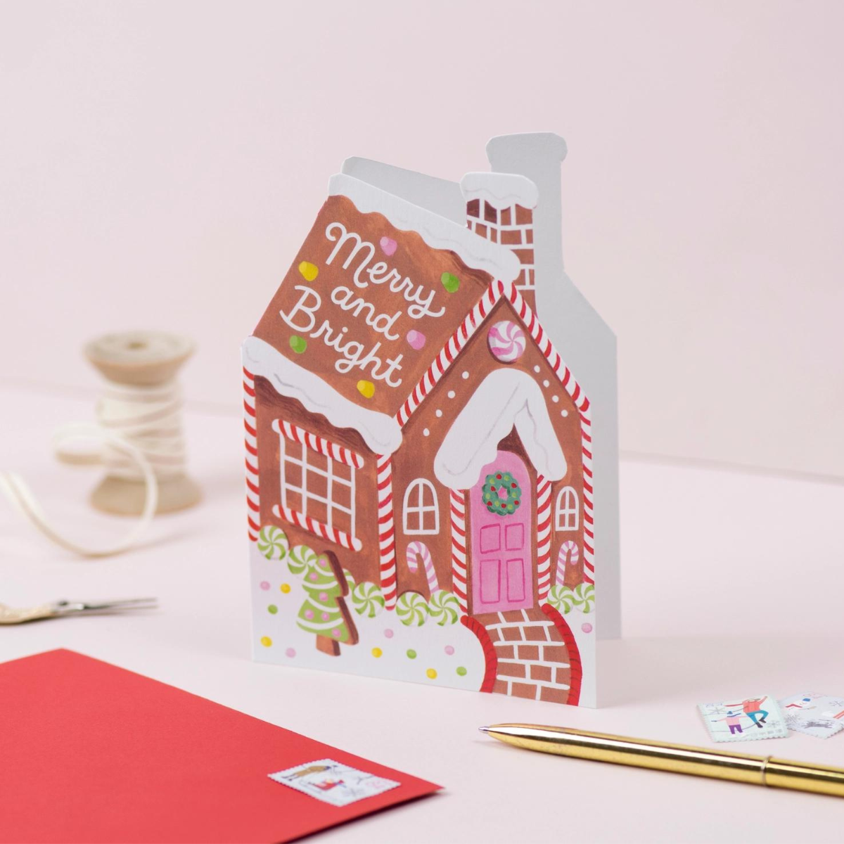 Cette charmante carte en forme de maison en pain d'épices évoque les douceurs de Noël.
