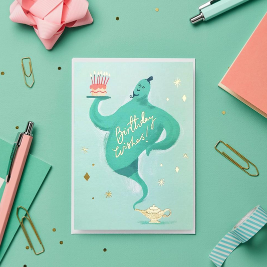 Le génie peint à la main tenant un délicieux gâteau sur cette carte d'anniversaire porte également une légende en feuille d'or pressée à la main sur laquelle on peut lire « Birthday Wishes ».