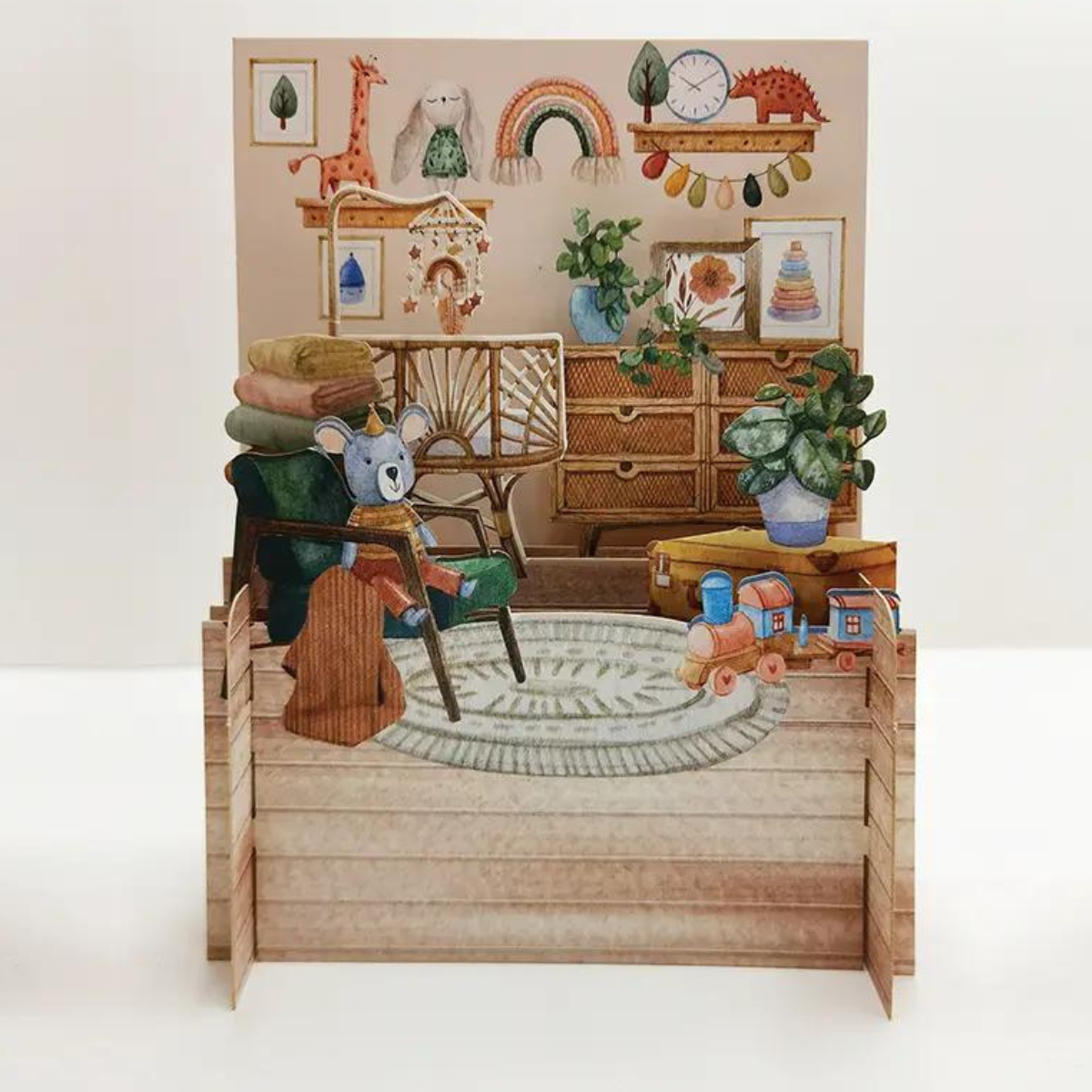Une fois dépliée, cette carte se transforme en une charmante chambre de bébé, remplie de jouets et d'un berceau douillet.
