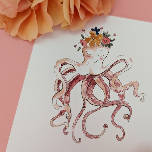 Carte ornée d'un très beau poulpe coiffé de fleurs. Il y a une inscription en bas de la carte : " Hello l'été ". Vous pouvez écrire votre message au dos.