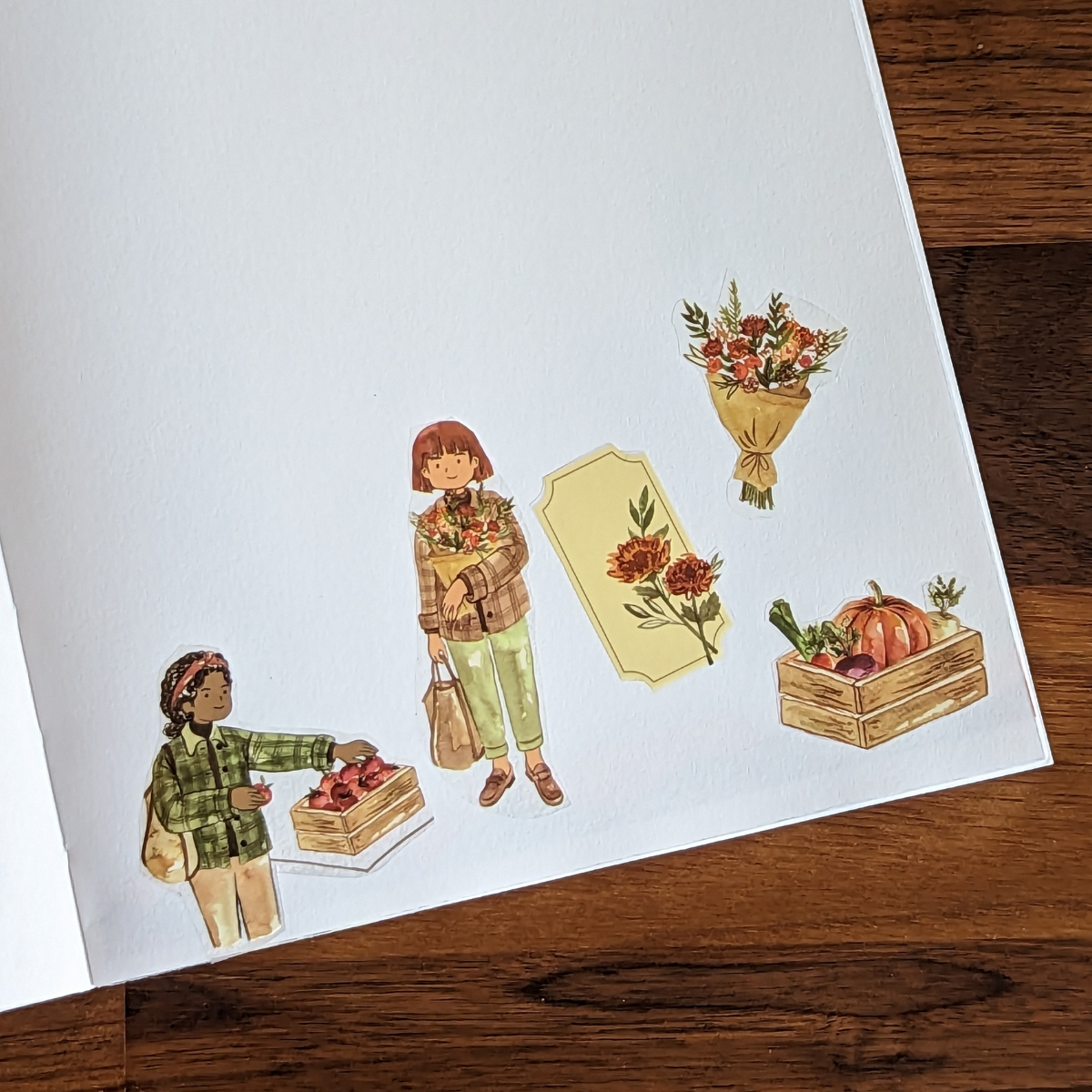 Des illustrations à l'aquarelle dessinées à la main de deux filles faisant leurs courses au marché ont été représentées.