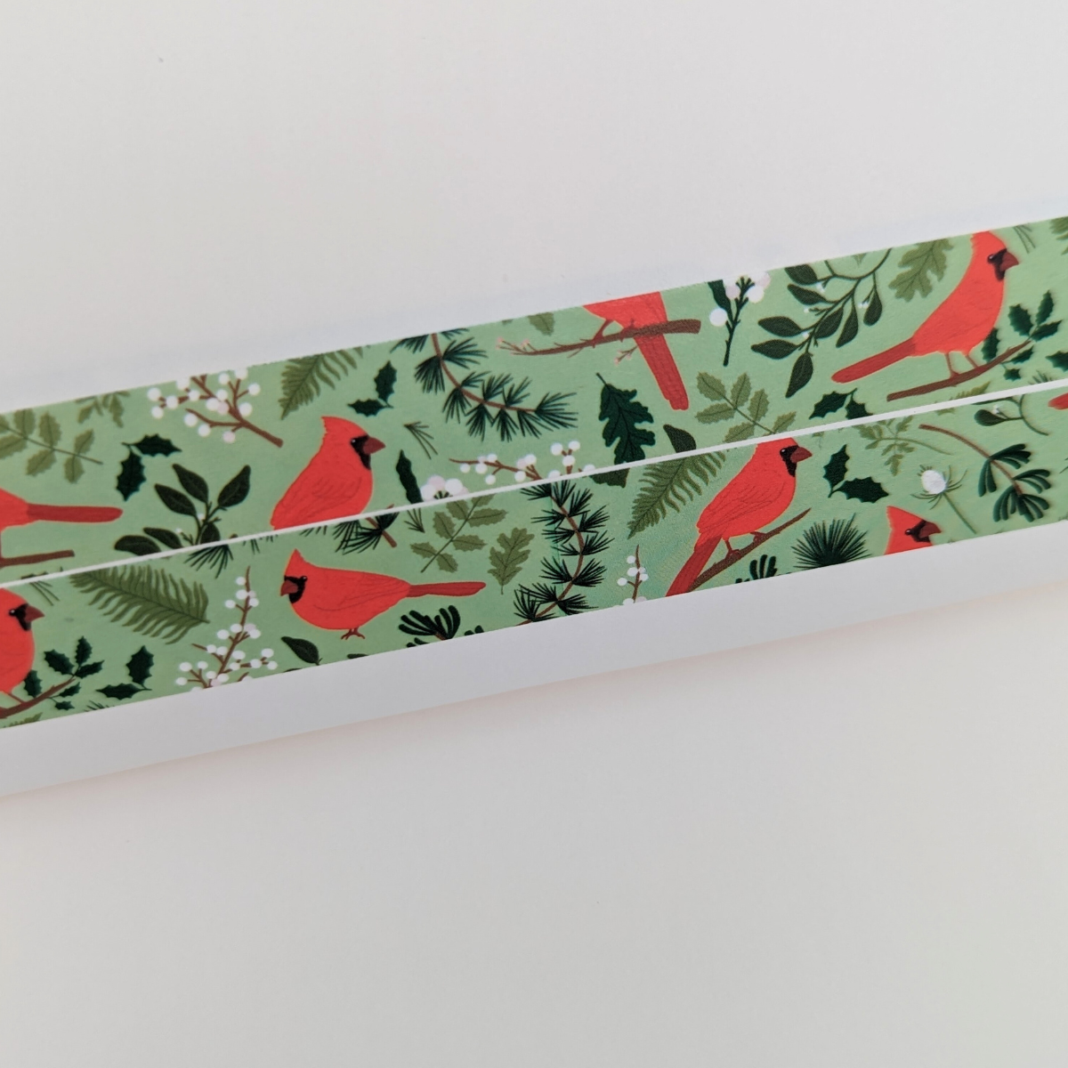 Pour ajouter une touche de féérie à vos projets créatifs, ce rouleau de masking tape décoré d'un cardinal rouge est parfait pour embellir vos cartes de vœux, cadeaux et décorations de Noël.