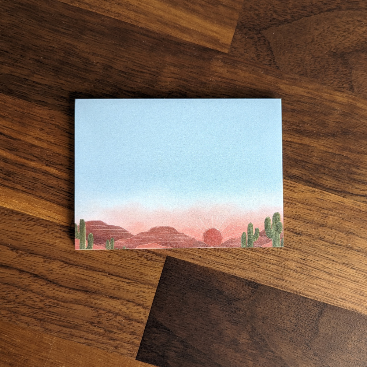 Post-it avec illustration d'un coucher de soleil sur un parc de cactus.