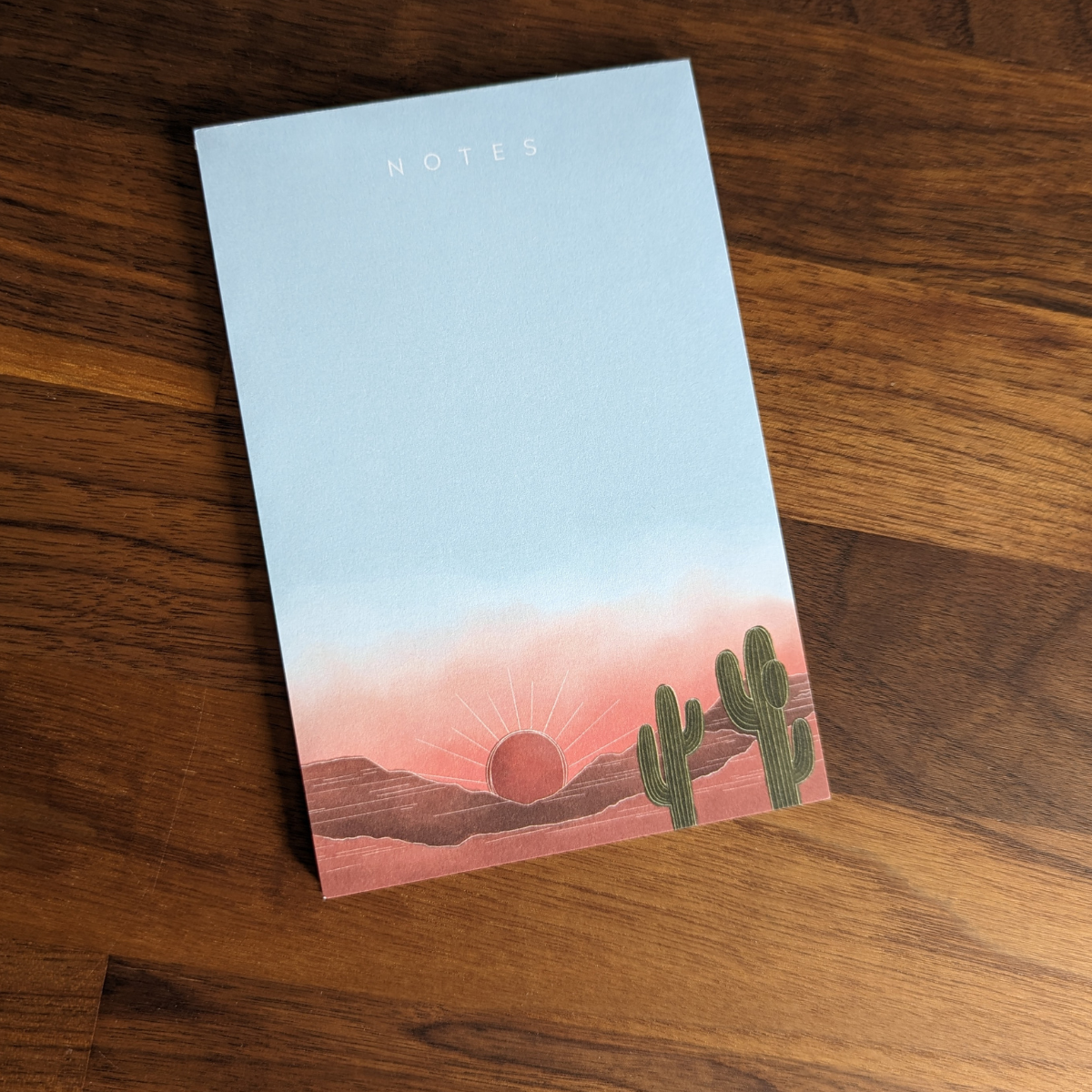 Bloc-notes de 50 feuilles avec coucher de soleil sur un parc de cactus dans le désert.