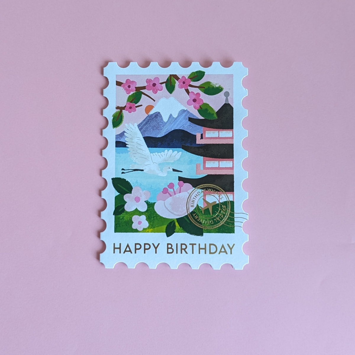 Cette carte en forme de timbre arbore une superbe illustration du Mont Fuji. Le cachet doré de la poste affiche les mots « Birthday Wishes », ce qui ajoute une touche d’authenticité.