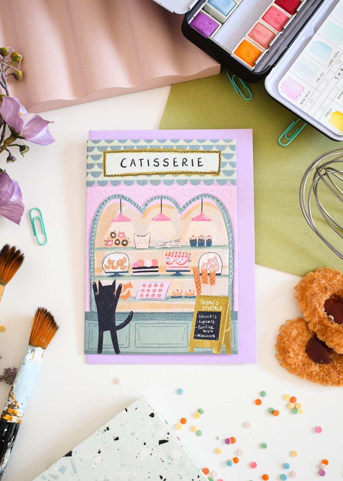 Carte de vœux illustrée avec un chat devant une pâtisserie, illustration originale Niaski.