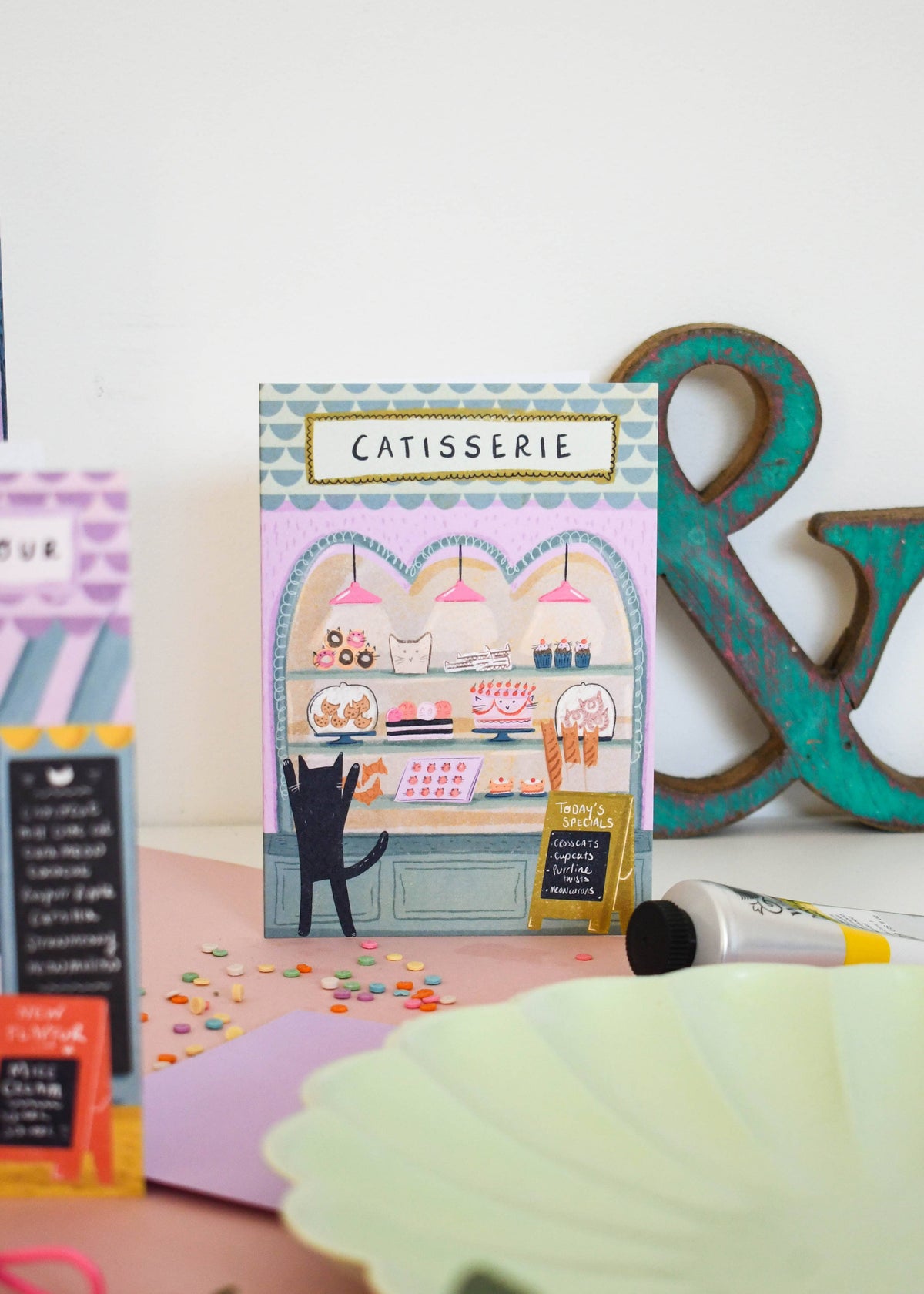 Carte de vœux illustrée avec un chat devant une pâtisserie, illustration originale Niaski.