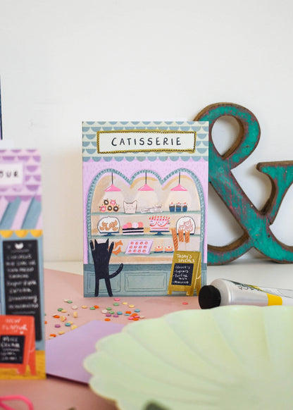 Carte de vœux illustrée avec un chat devant une pâtisserie, illustration originale Niaski.