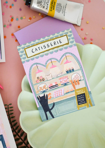 Carte de vœux illustrée avec un chat devant une pâtisserie, illustration originale Niaski.