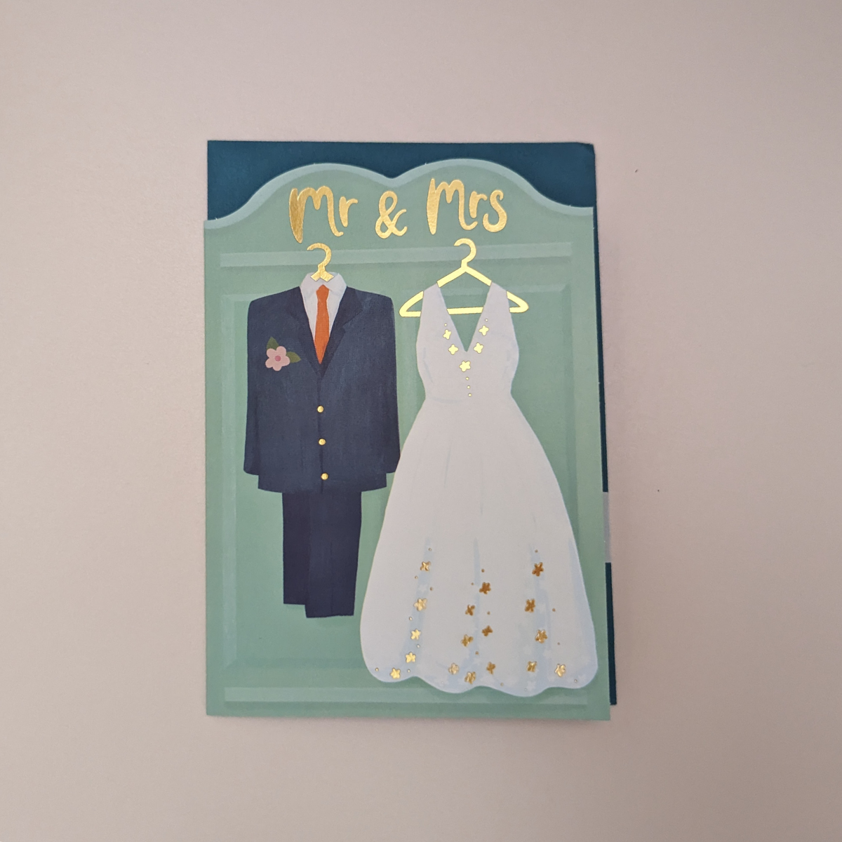Avec un costume bleu marine pour le marié, une robe de mariée en dentelle blanche avec des détails dorés et une inscription « Mr & Mrs » finie dans une feuille d'or de luxe, c'est une carte vraiment digne de célébrer une belle journée. et d'envoyer vos vœux de mariage.