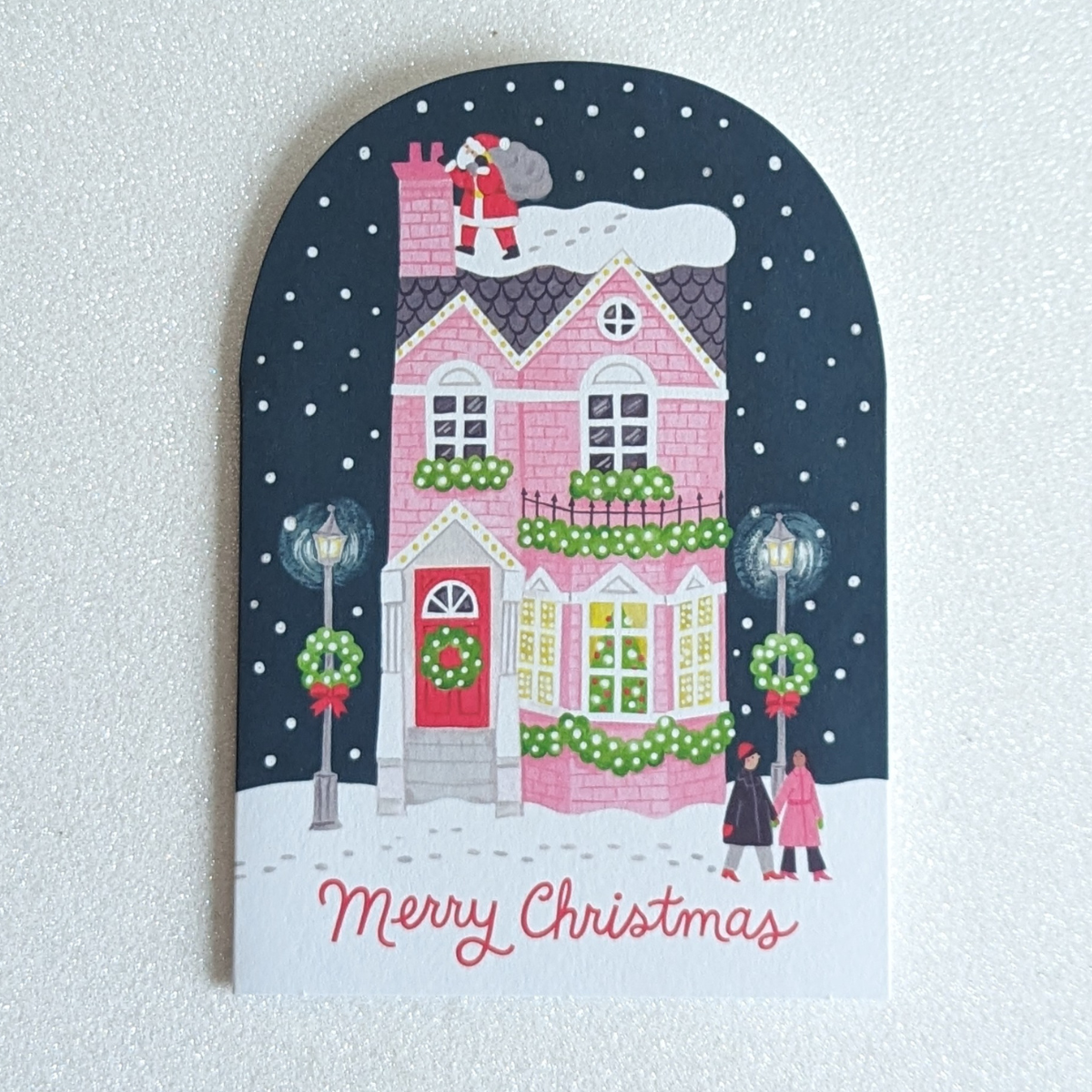 La maison rose joliment décorée et le Père Noël près de la cheminée créent une image qui évoque instantanément la féerie des fêtes.