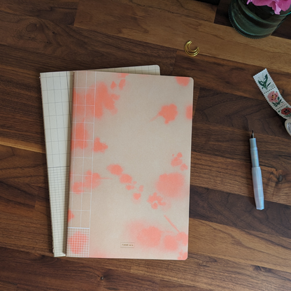 Deux cahiers d'exercices lignés pour vous accompagner dans vos aventures créatives. Sur la couverture, une aquarelle de cerisier japonais et sur le second une grille graphique.