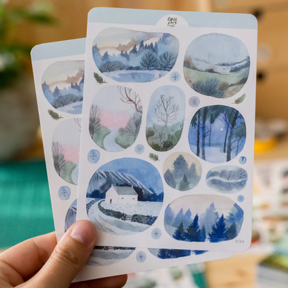 Stickers paysages d’hiver The Wild Pencil aux illustrations de forêts, neige, montagnes et chemins dans des tons bleus.