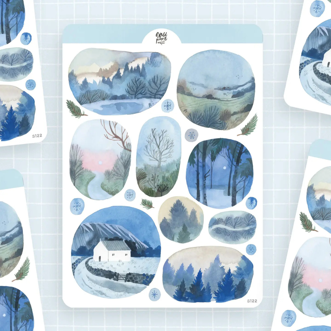 Planche de stickers The Wild Pencil avec paysages d’hiver, forêts enneigées, montagnes et petite maison sous la neige.