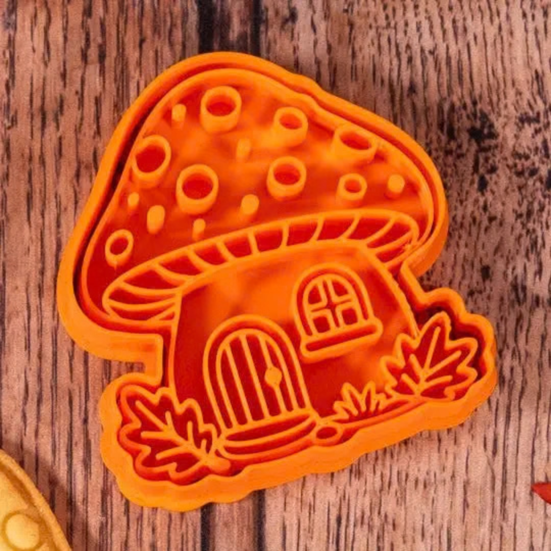Emporte-pièce en forme de maison champignon avec porte, fenêtre, feuilles et petits détails.